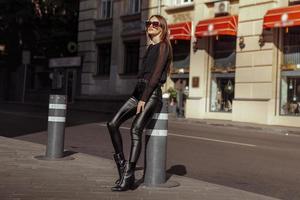 Model posiert in Lederkombi und Sonnenbrille in der Stadt foto