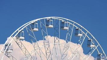 großes Riesenrad gegen blauen Himmel und weiße Wolken foto