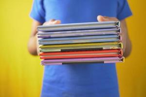 Hand, die Stapel Bücher auf farbigem Hintergrund hält foto