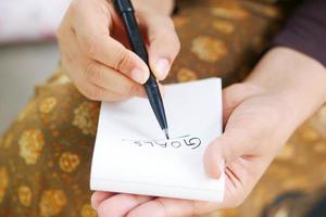 Frauen hand schreiben Ziele auf einem Notizblock foto