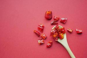 rote Chiliflocken, die auf rotem Hintergrund verschüttet werden foto