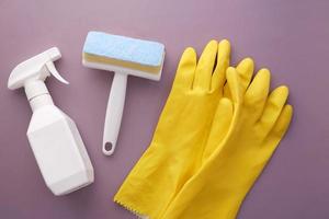 Fensterreinigungsspray, Bürste und Handschuhe auf violettem Hintergrund foto