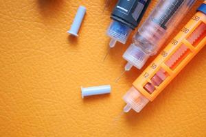 Insulinpens auf orangefarbenem Hintergrund foto