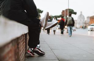 Teenager und Mädchen sitzen zusammen auf der Straße, wo man ihre Beine sehen kann. foto