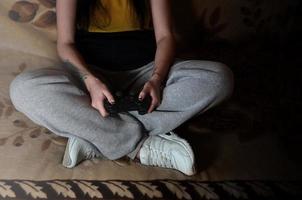 Ein junges Mädchen spielt Videospiele mit einem schwarzen Joystick mit vielen b foto
