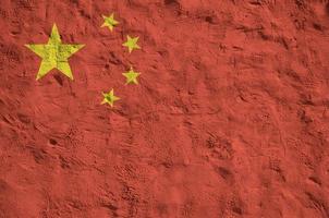 china-flagge in hellen farben auf alter reliefverputzwand dargestellt. strukturierte Fahne auf rauem Hintergrund foto