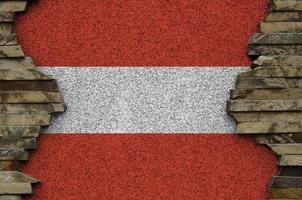 Österreich-Flagge in Lackfarben auf alten Steinmauern in der Nähe dargestellt. strukturiertes banner auf felswandhintergrund foto