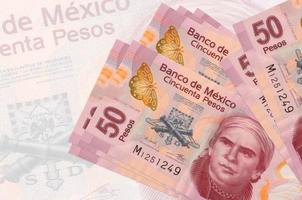 50 mexikanische Peso-Scheine liegen im Stapel auf dem Hintergrund einer großen halbtransparenten Banknote. abstrakte Darstellung der Landeswährung foto