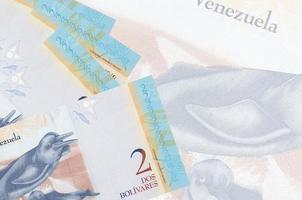 2 venezolanische Bolivar-Scheine liegen im Stapel auf dem Hintergrund einer großen halbtransparenten Banknote. abstrakter betriebswirtschaftlicher hintergrund foto