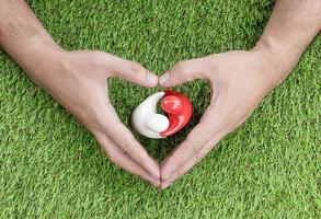 Draufsicht Mock-up Paar umarmt auf Grasboden mit Herzsymbol in der Hand. Valentinstag-Konzept foto