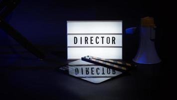 Regiestuhl mit Kino-Lightbox-Schild-Regisseur-Text darauf und Klappen-Megaphon foto