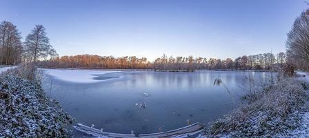 Panoramabild des zugefrorenen Sees bei frostiger Temperatur bei Sonnenaufgang foto