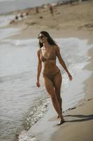 junge Frau im Bikini, die an einem Sommertag am Meer spazieren geht foto