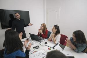 Executive Leader im Gespräch mit einer glücklichen, vielfältigen Mitarbeitergruppe bei einer Unternehmensbürobesprechung, foto