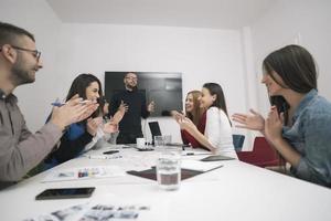 Executive Leader im Gespräch mit einer glücklichen, vielfältigen Mitarbeitergruppe bei einer Unternehmensbürobesprechung, foto