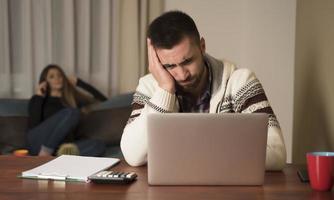 junge paare, die finanzen verwalten und ihre bankkonten mit einem laptop überprüfen. frau und mann erledigen zusammen papierkram und zahlen online steuern auf notebook-pc foto