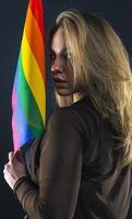 lesbische Frau mit Regenbogenfahne isoliert auf schwarzem Hintergrund. lgbt internationales symbol der lesbischen, schwulen, bisexuellen und transgender-gemeinschaft. foto