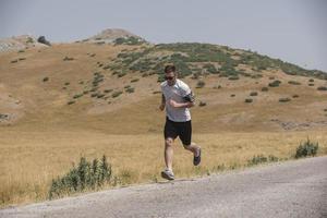 sportlicher Läufer, der im Sommer auf dem Bergplateau läuft foto
