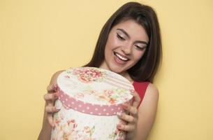 Porträt eines glücklich lächelnden Mädchens, das eine Geschenkbox öffnet foto