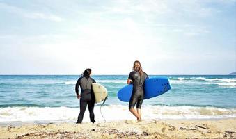 Surferpaar wartet auf die hohen Wellen am Strand - sportliche Menschen mit Surfbrettern am Strand - Extremsport- und Urlaubskonzept foto