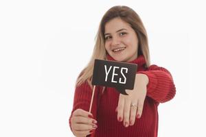 Frau mit Verlobungsring und Schild mit der Aufschrift Ja foto