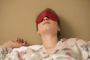 eine junge Frau, die mit einer augenbedeckenden Maske schläft. foto