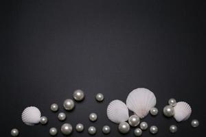 Muscheln und Perlen auf schwarzem Hintergrund, mit freiem Platz für Text. foto