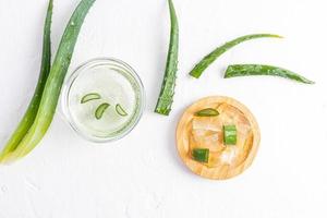 Stücke von transparentem Zellstoff aus Aloe-Vera-Blättern in einer Holzschale auf weißem Hintergrund zwischen den saftigen Blättern der Pflanze. natürliche Hautpflege. foto