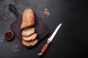 Köstliches knuspriges Brot mit Müsli, das auf einem Holzschneidebrett in Scheiben geschnitten wird foto