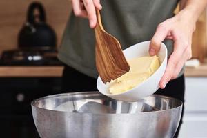 Hände geben Butter in eine Schüssel. Kochrezept foto