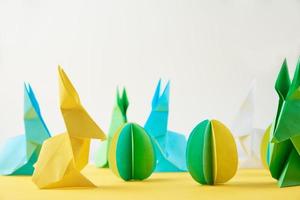 Papier-Origami-Esater-Kaninchen und farbige Eier auf gelbem Hintergrund foto