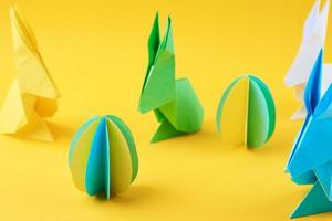 Papier-Origami-Esater-Kaninchen und farbige Eier auf gelbem Hintergrund foto