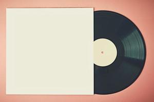 Alte Retro-Vinyl-Schallplatte in Papierhülle auf rosa Hintergrund, Attrappe. Vintage getöntes Foto