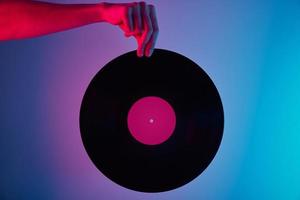 Hand halten Retro-Vinyl-Disc mit Neon-Hintergrund foto