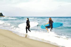 Surferpaar wartet auf die hohen Wellen am Strand - sportliche Menschen mit Surfbrettern am Strand - Extremsport- und Urlaubskonzept foto