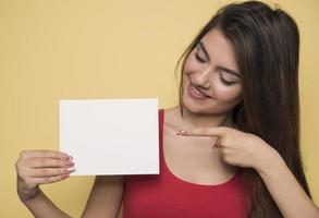 junge lächelnde frau, die ein leeres blatt papier für werbung hält foto