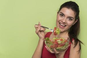 Porträt eines glücklichen, verspielten Mädchens, das frischen Salat aus einem Bogen isst foto