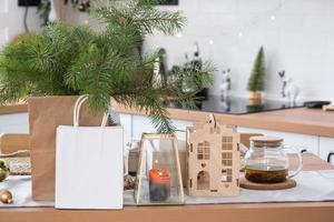 papierpakete mock-up sind auf dem küchentisch serviert, der für weihnachten dekoriert ist. Einkäufe und Geschenke, Geschenke und Fertiggerichte werden geliefert und für das neue Jahr zubereitet foto