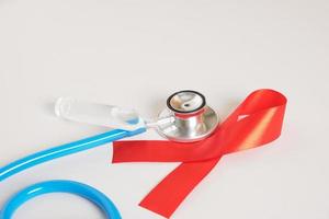 rotes band und blaues medizinisches stethoskop gesundheitswesen und safer-sex-konzept. foto