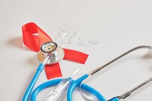 rotes band und blaues medizinisches stethoskop gesundheitswesen und safer-sex-konzept. foto