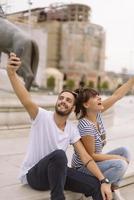 ein paar touristen, die spaß haben, im urlaub auf der straße der stadt spazieren zu gehen - glückliche freunde, die im urlaub zusammen lachen - menschen- und urlaubskonzept foto