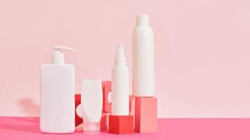 mehrere verschiedene weiße plastikflaschen und rohre auf rosa geometrischen podien auf rosa hintergrund foto
