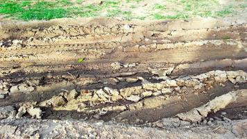 Cartire-Spuren auf dunkelbraunem Feldweg, verursacht durch Regenwasser foto