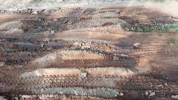 Cartire-Spuren auf dunkelbraunem Feldweg, verursacht durch Regenwasser foto