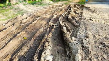 Cartire-Spuren auf dunkelbraunem Feldweg, verursacht durch Regenwasser foto