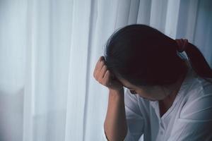 Schizophrenie mit einsamem und traurigem Depressionskonzept der psychischen Gesundheit. depressive frau, die zu hause auf dem boden sitzt und sich in einem dunklen raum unglücklich fühlt. Frauen sind depressiv, ängstlich und unglücklich. foto