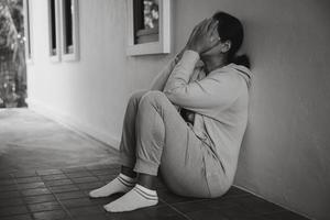 Schizophrenie mit einsamem und traurigem Depressionskonzept der psychischen Gesundheit. depressive frau, die zu hause auf dem boden sitzt und sich in einem dunklen raum unglücklich fühlt. Frauen sind depressiv, ängstlich und unglücklich. foto