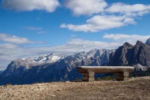 Holzbank und im Hintergrund Blick auf die Berggipfel. Provinz Belluno, Dolomiten, Italien