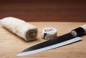 Sushi und Messer auf einem Holzschneidebrett foto