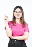 zeigt Produkt und zeigt Seite mit dem Zeigefinger der schönen asiatischen Frau isoliert auf weiß foto